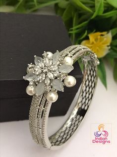 Wear this stunning bracelet as an everyday essential! This delicate and feminine bangle bracelet features a sparkling silver finish, studded with colorful stones. The beautiful handcrafted design will be sure to make any outfit stand out. Rhodium Plated silver tone clasp openable bangle bracelet in floral design studded with pearls. The size of these bangle bracelet is fit for 2.6 to 2.8 as it is an openable kada bangle.