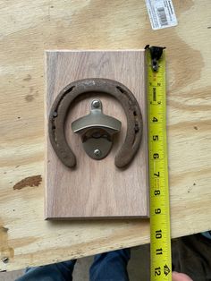 a piece of wood with a metal ring on it and a measuring tape next to it