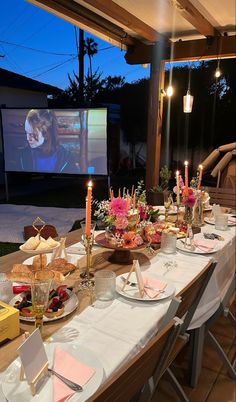 a long table is set up with food and candles for an outdoor movie night party