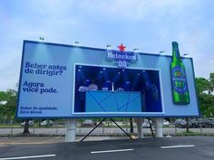 an advertisement for heinekent beer on the side of a road in front of a parking lot