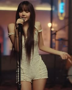 a woman with long hair standing in front of a microphone