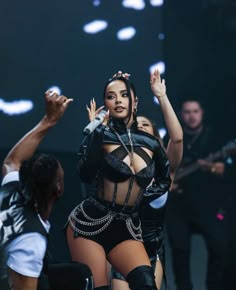 the singer is performing on stage with her hands in the air and other dancers behind her