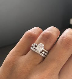 a woman's hand with a diamond ring on top of her finger and the other hand holding an engagement ring