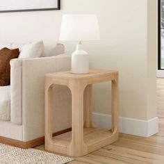 a white couch sitting next to a wooden table on top of a hard wood floor