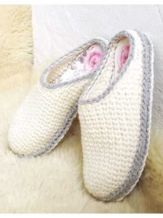 two crocheted slippers sitting on top of a fluffy white blanket next to a stuffed animal