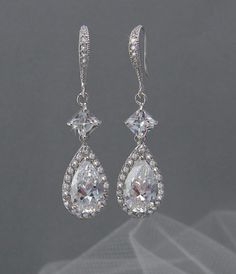 a pair of diamond earrings on a gray background