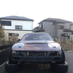 the front end of a car that is parked in a lot next to some houses