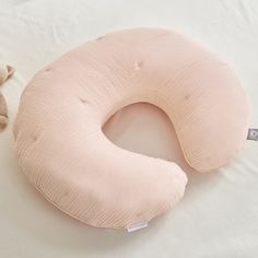 a pink pillow sitting on top of a bed next to a teddy bear