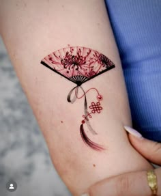 a woman's arm with a fan tattoo on it