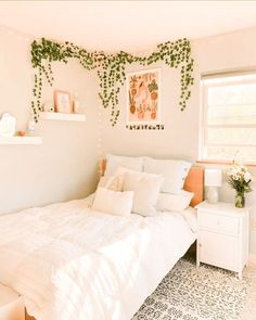 a bedroom with white bedding and plants on the wall