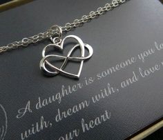 a necklace with two intertwined hearts hanging from it's center on a card