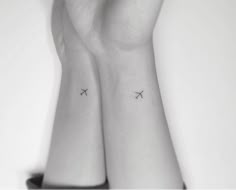 two small tattoos on the wrist that are both black and white, one with an airplane