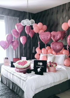 a bed with pink and white balloons hanging from the ceiling