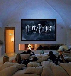 two people laying on bean bag chairs in front of a harry potter movie poster and fireplace