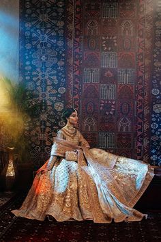 a woman sitting on top of a couch in front of a wall covered in rugs