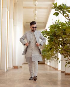 a man walking down a hallway with sunglasses on