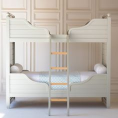 a white bunk bed sitting in a bedroom next to a wall with paneled panels