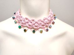 a pink crocheted necklace with beads on a mannequin headdress