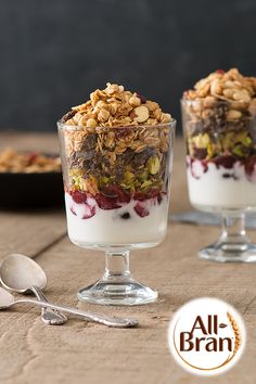 two glasses filled with granola and yogurt on top of a wooden table