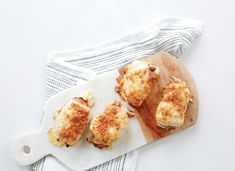 three scallops on a cutting board next to a white dish towel and cloth