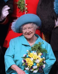 an older woman wearing a blue hat and holding flowers