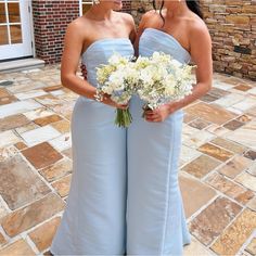 two bridesmaids in blue dresses holding bouquets