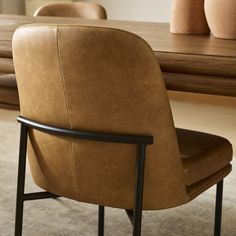 a brown leather chair sitting in front of a wooden table