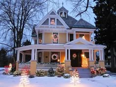 a large house with christmas lights on the front porch and wreaths around the windows