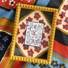 an embroidered square on top of a colorful cloth with beadwork work in the middle