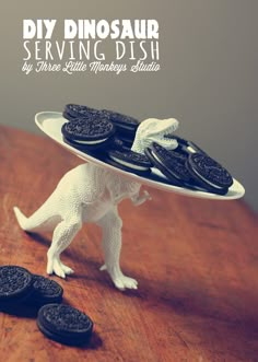 a toy dinosaur holding a plate with cookies on it's back and the words serving dish written in white