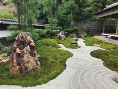 a garden with rocks, grass and trees in the background at a japanese style house