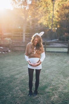 a woman standing in the grass wearing bunny ears