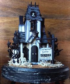 a black and white halloween house on top of a table with spooky decorations