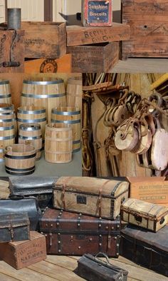 several old trunks are stacked on top of each other in front of wooden crates and barrels