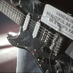 a close up of an electric guitar with a sign on it's neck that says, vandalism is beautiful as all in vapors