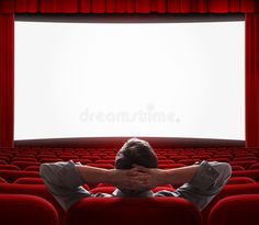 a man sitting in front of an empty theater seat with his hands on his face