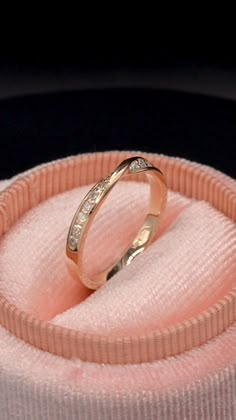 a wedding ring sitting on top of a pink cloth covered box with its lid open