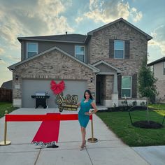 a woman standing in front of a house with a red ribbon on the driveway and a sign that says sell