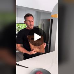 a man holding a wooden cutting board next to a plate of food on a counter