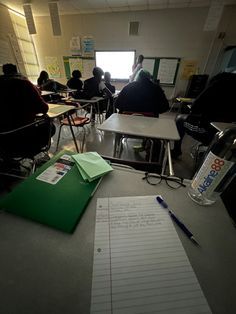 an empty classroom with students sitting at desks and writing on lined paper in front of them