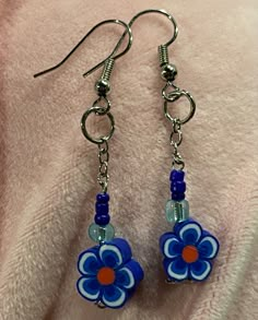 blue and orange flower dangle earrings on a pink blanket with silver earwires