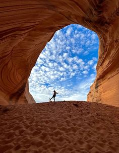 a person standing in the middle of a desert with a blue sky and white clouds