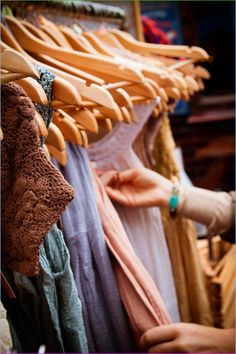 a woman is looking at clothes hanging on a rack