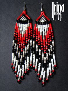 red, white and black beaded earrings are hanging from hooks on a black surface