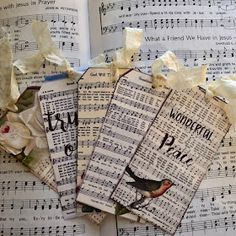 three pieces of paper with words and flowers on them sitting in front of sheet music