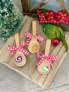 three wooden spoons with designs on them sitting on a tray next to christmas decorations