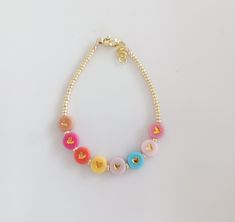 a bracelet made with beads and charms on a white surface, showing the letter o