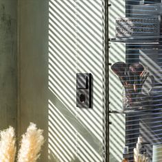 an image of a window with blinds in the sun coming through it and a vase behind it