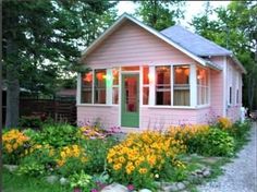 a small pink house surrounded by flowers and trees