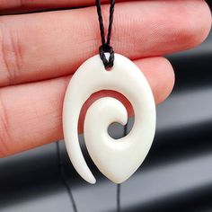 a hand holding a white and red necklace with a spiral design on the back of it